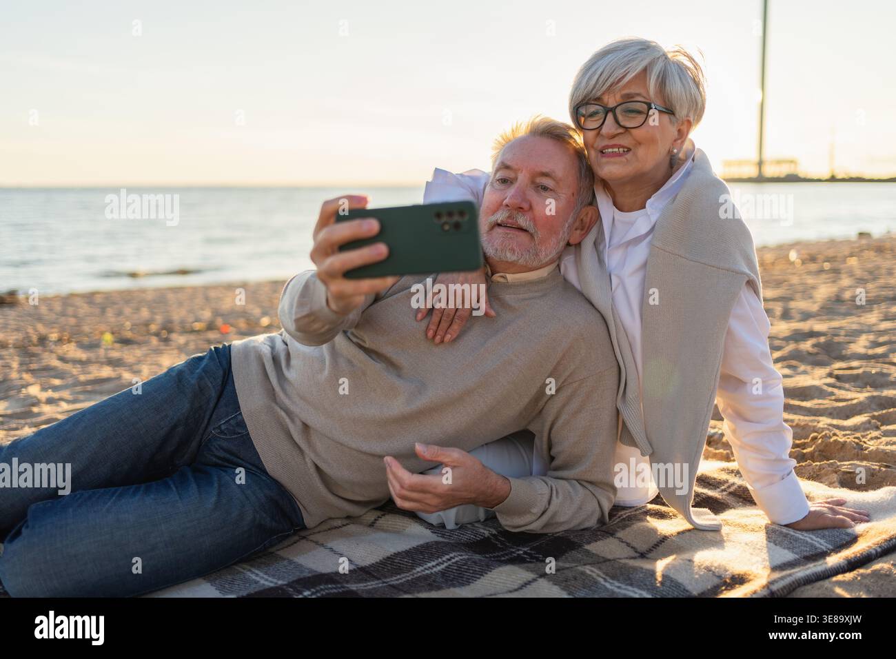 Videoanruf. Seniorenpaar, das Selfie macht, mit Videoanruf am Strand draußen. Großvater spricht online. Moderne Technologie der älteren Generation. Online-Chat für virtuelle Meetings Stockfoto