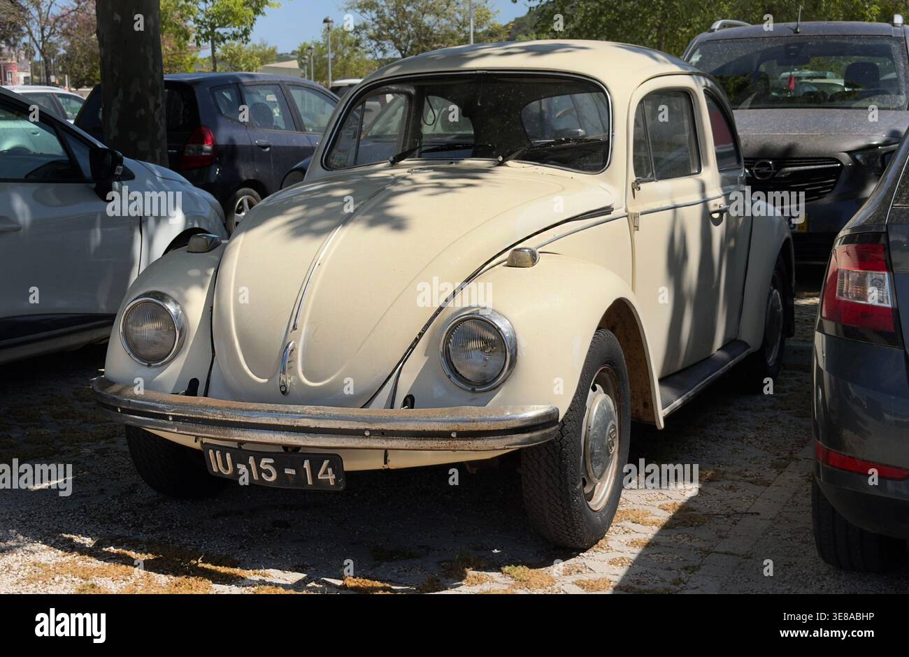 Der weiße Vintage-Klassiker Volkswagen Käfer parkte auf einem Grundstück unter Baumschatten in Portugal Stockfoto