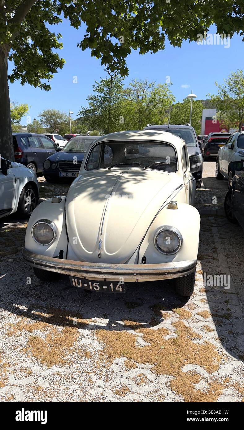 Der weiße Vintage-Klassiker Volkswagen Käfer parkte auf einem Grundstück unter Baumschatten in Portugal Stockfoto
