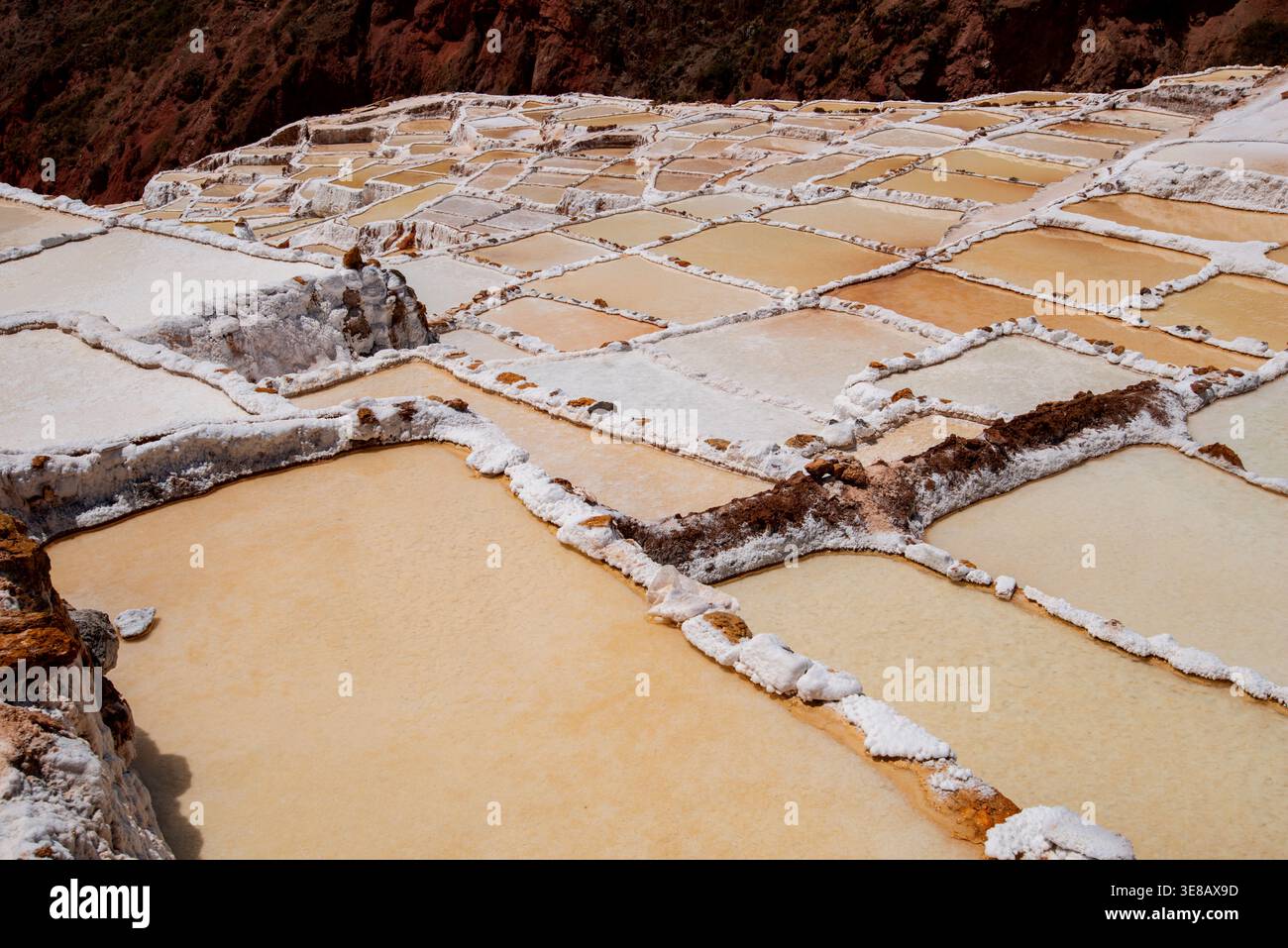 Terrassen-Salinen, die in den Andenhang bei Maras in Peru eingemeißelt wurden und die geometrischen Muster des traditionellen Bergbaus zeigen. Stockfoto