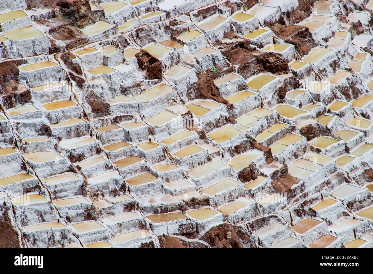 Terrassen-Salinen, die in den Andenhang bei Maras in Peru eingemeißelt wurden und die geometrischen Muster des traditionellen Bergbaus zeigen. Stockfoto