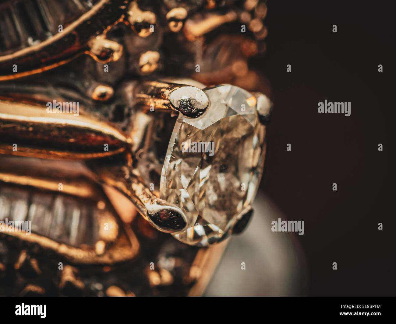 Detailaufnahme eines Diamanten im Kissenschliff und kleinerer Baguette-Diamanten, die in einem raffinierten Verlobungsring aus Vintage-Gold gefasst sind Stockfoto