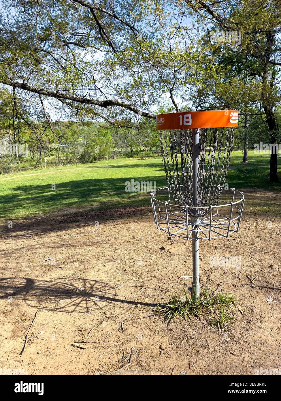 Disc Golfkorb auf einem Dreck- und Grasplatz Stockfoto