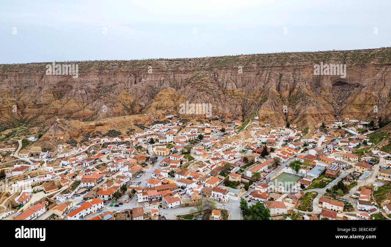Ein Blick aus der Vogelperspektive fängt das malerische weiße Dorf Gorafe am Fuße einer imposanten Klippe im Granada Geopark ein. Typische Häuser mit roten Dächern Stockfoto