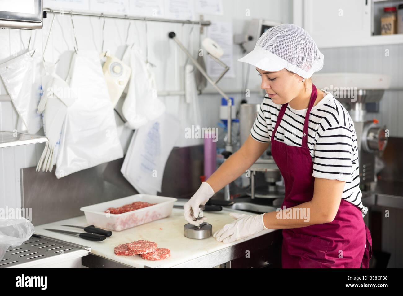 Kochen halbfertiger Produkte - Mädchen bereitet Fleischkoteletts mit speziellen Geräten zu Stockfoto