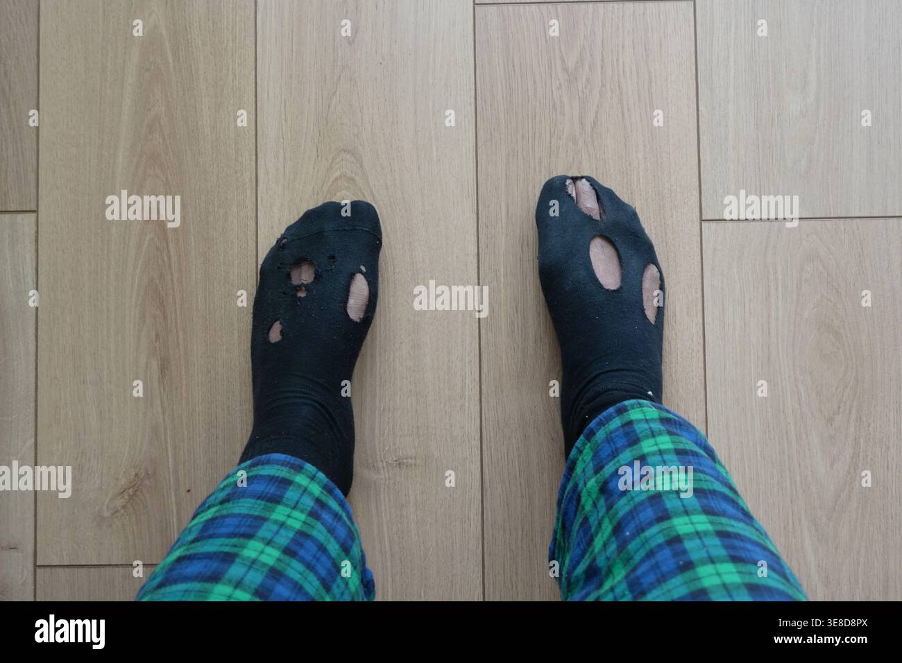 Getragene Socken an einer Person, die auf einem Holzboden steht Stockfoto
