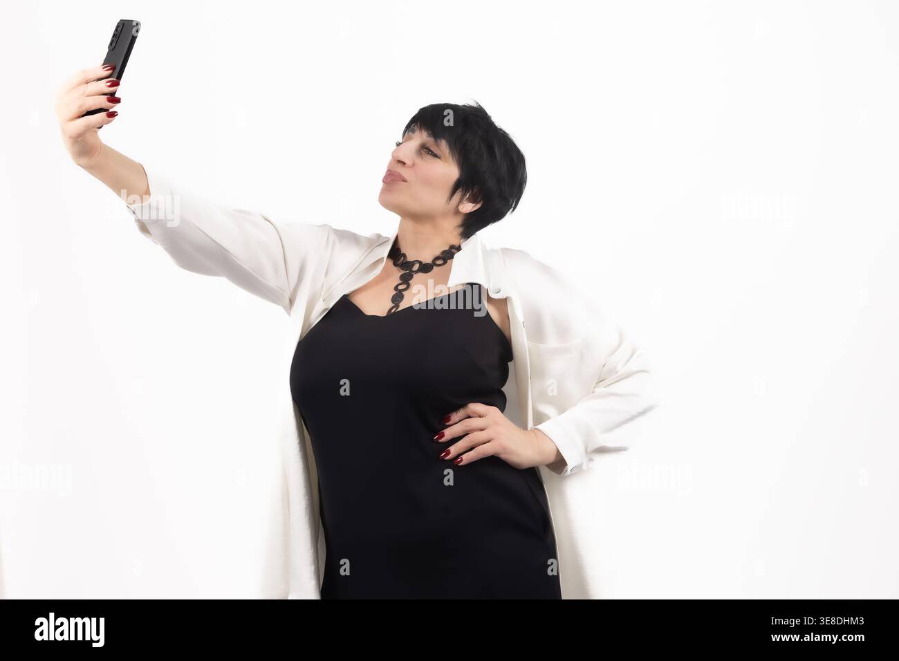 Frau, die ein Selfie mit einem Telefon auf weißem Hintergrund macht Stockfoto