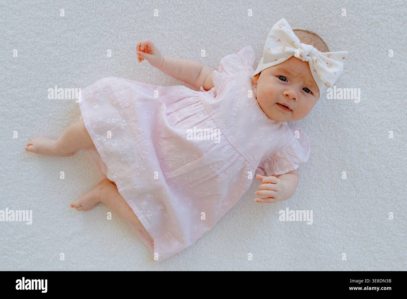 Mädchen in rosa Kleid auf weißem Hintergrund, von oben gesehen. Minimale Zusammensetzung mit Kopierraum bereinigen. Ideal für Eltern und Babyprodukte Stockfoto