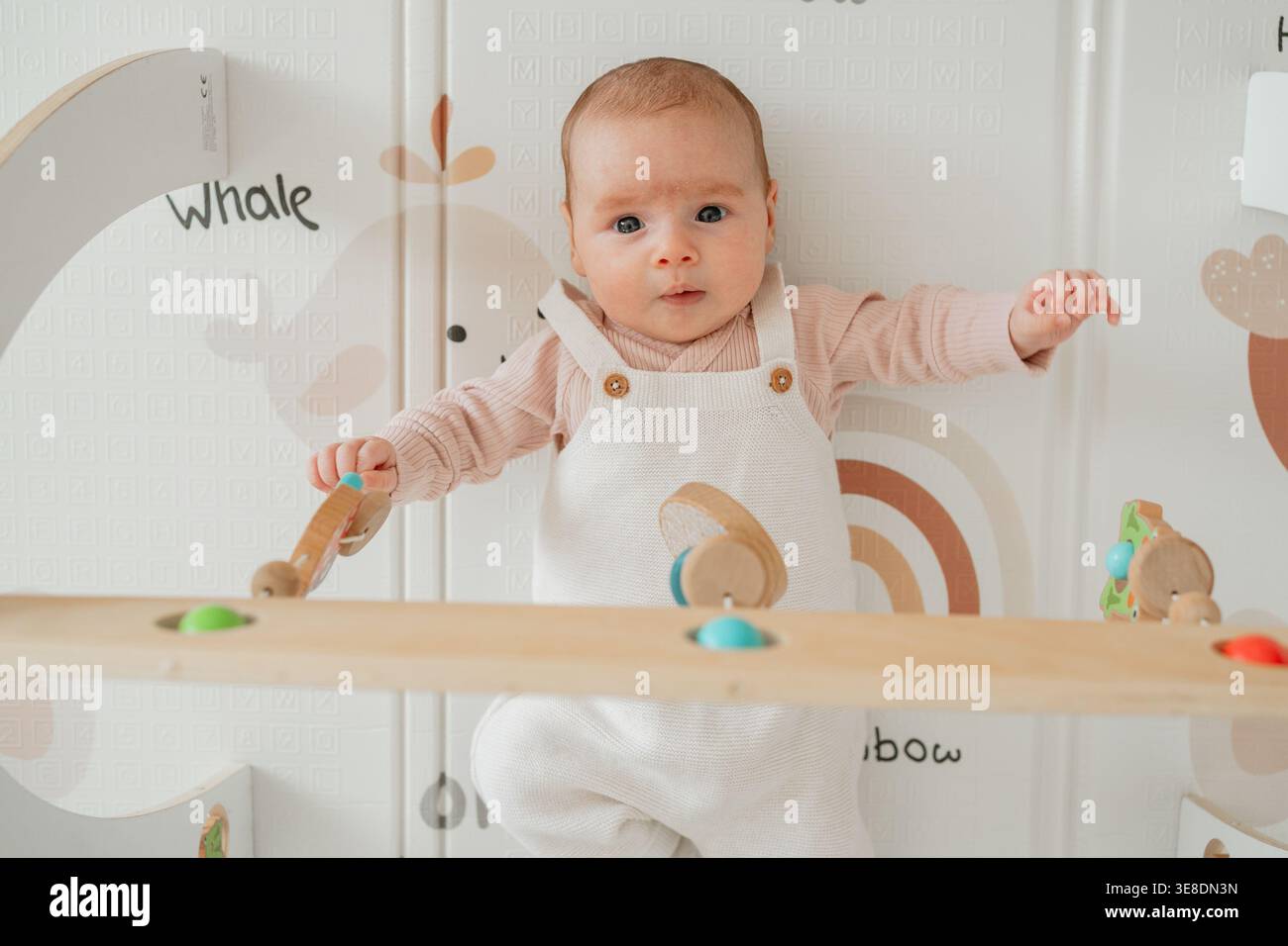 Kind liegt auf einer weichen Aktivmatte und sieht sich beim Spielen um. Gemütliches Wohnumfeld, das frühkindliche Entwicklung und Babyforschung zeigt. Stockfoto