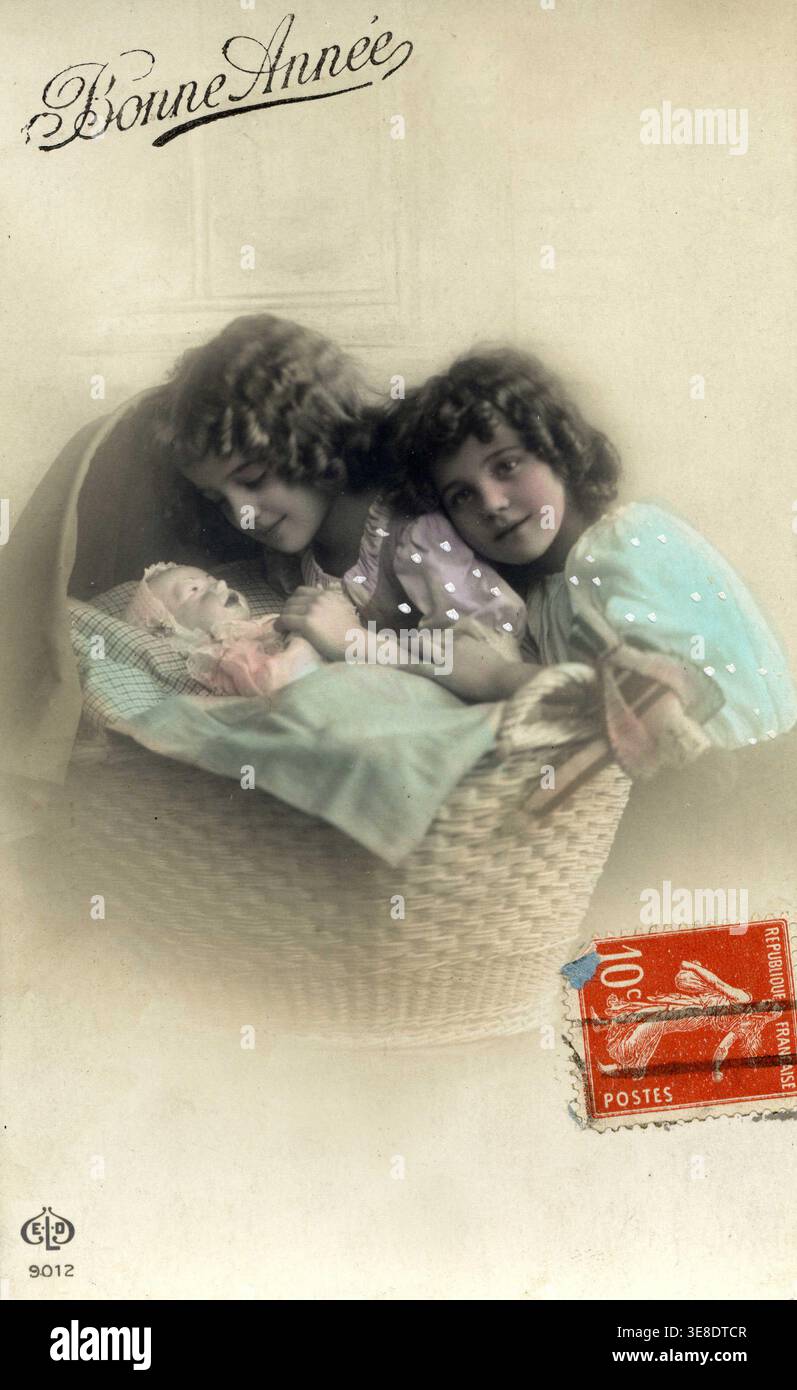 Deux petites Files (soeurs) jouant a mA maman avec leur poupee. Carte postale de voeux pour la nouvelle annee, Annexes 1920. Stockfoto