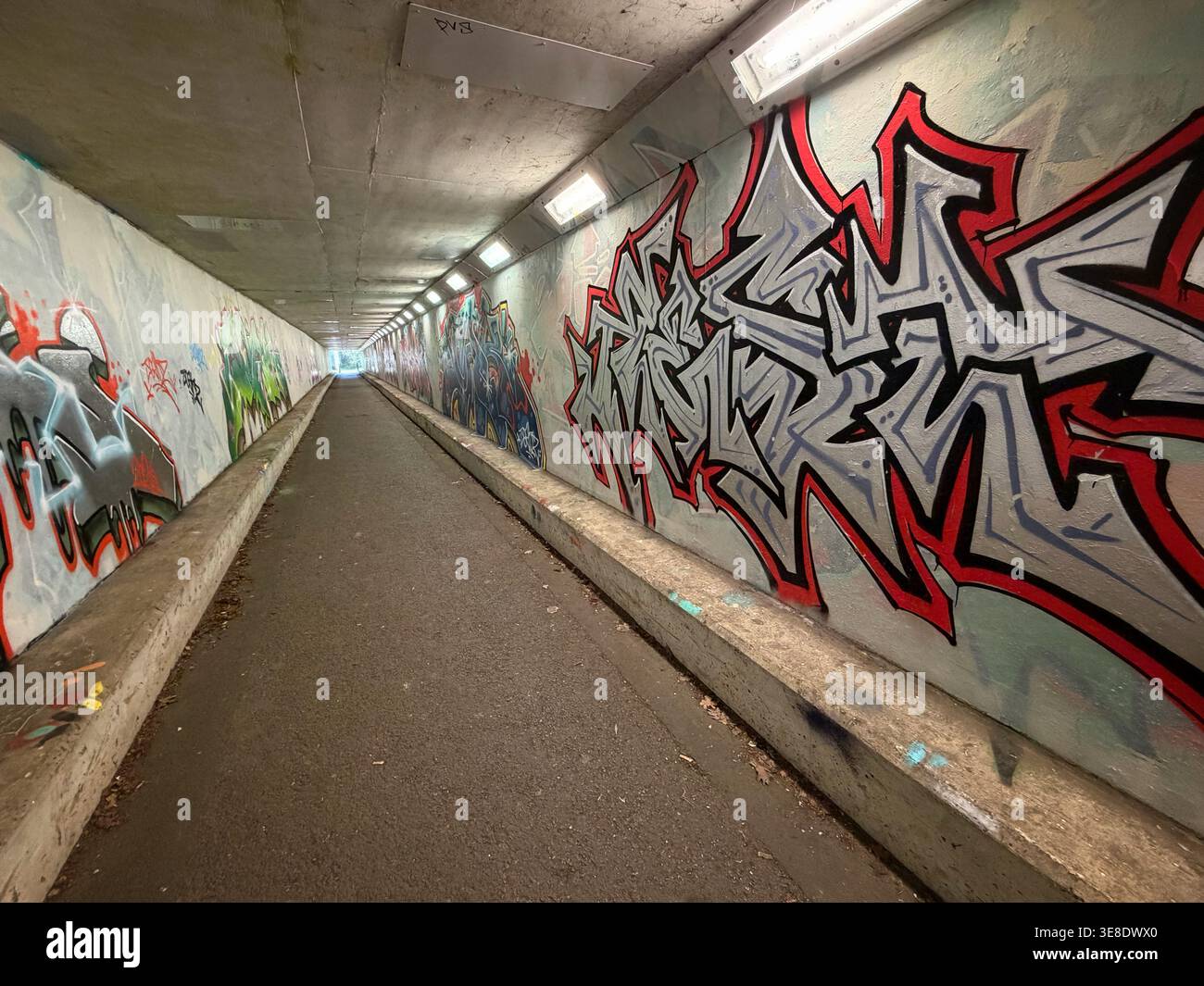 U-Bahn-Tunnel mit Graffiti an Wänden in der Nähe des Flughafens Gatwick, London, Großbritannien - Smartphone-aufgenommenes Stockfoto