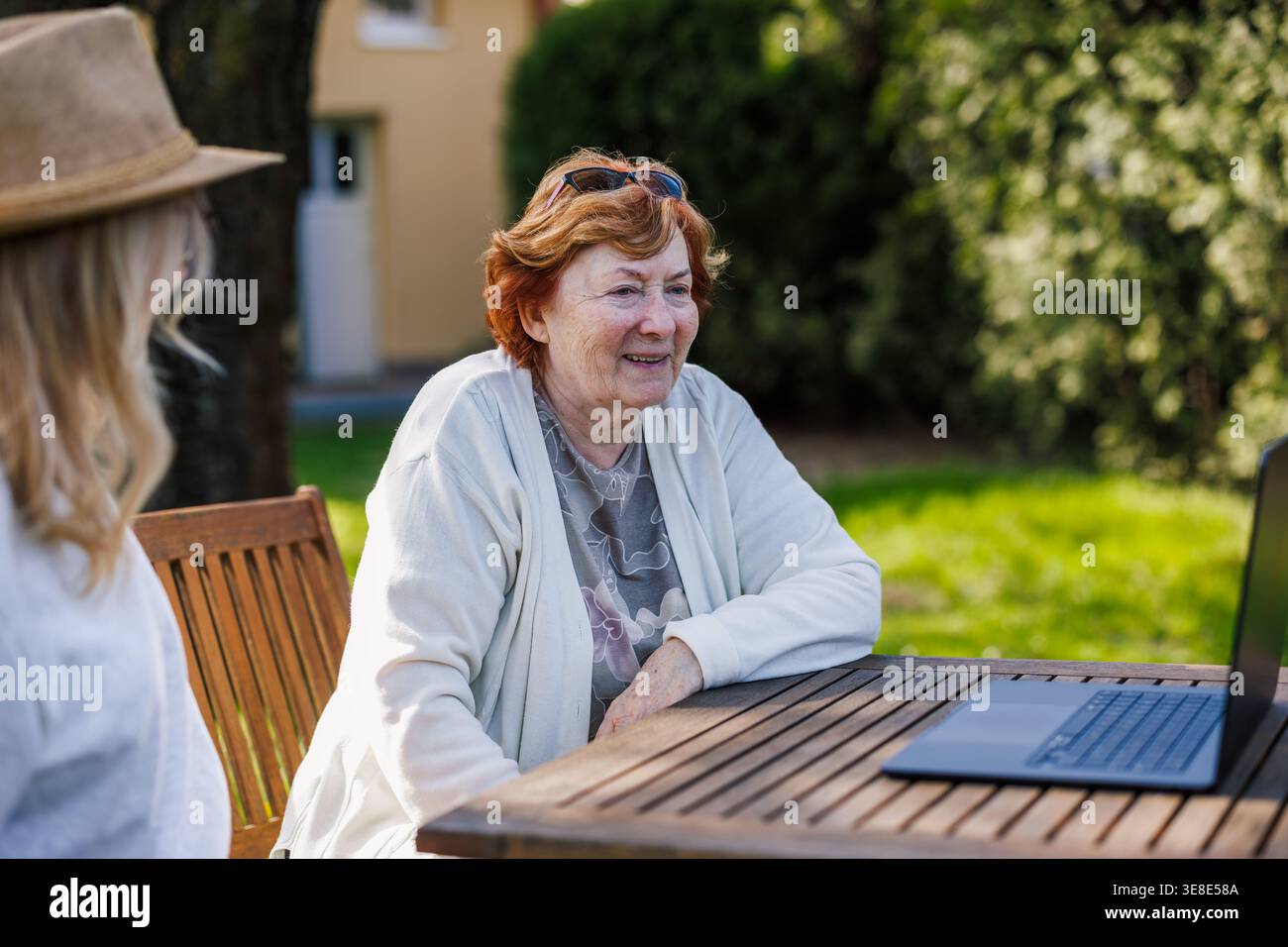 Lächelnde Seniorenmutter und erwachsene Tochter, die draußen auf den Laptop-Bildschirm schauen. Generationslückenkonzept mit moderner Technologie Stockfoto