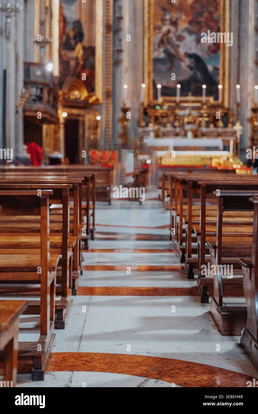 Holzbänke säumen den Kirchengang mit Kerzen und Altar am Ende Stockfoto