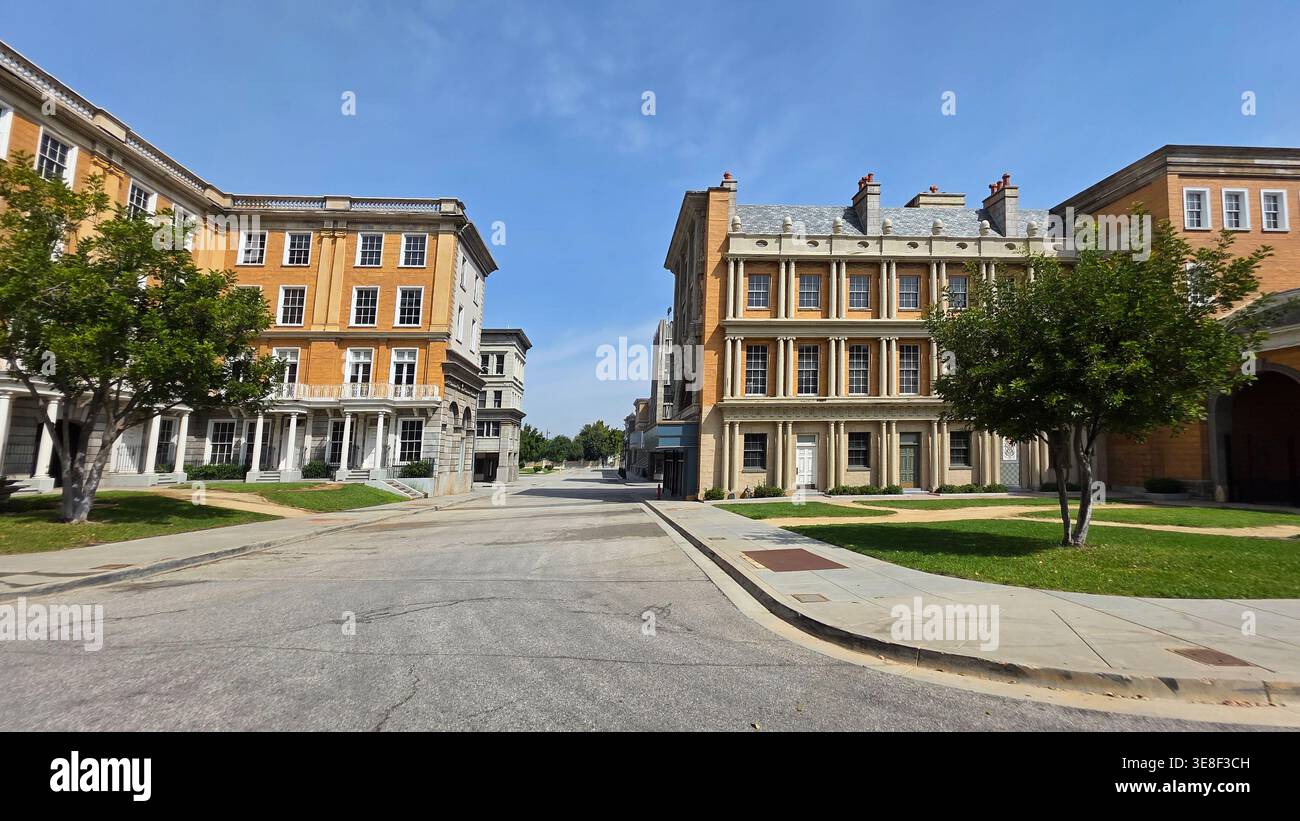Classic Studio Backlot Street Mit Historischen Fassaden. Großer Blick auf eine ruhige Straße, gesäumt von eleganten historischen Gebäudefassaden, grünen Rasenflächen und Stockfoto