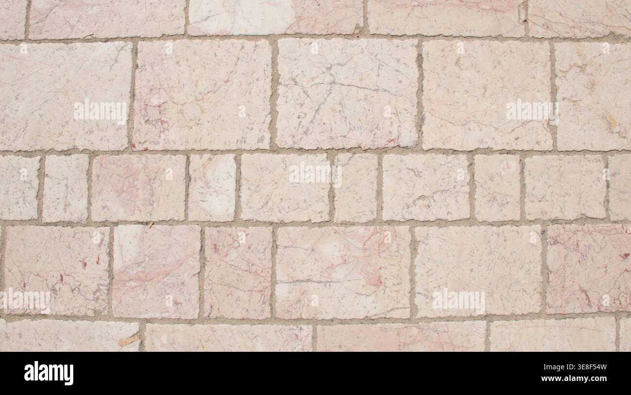 Hochauflösendes Bild einer hellen Marmorziegelwand mit dezenten rosa und grauen Adern. Die strukturierte orangene Steinziegeloberfläche ist angeordnet Stockfoto