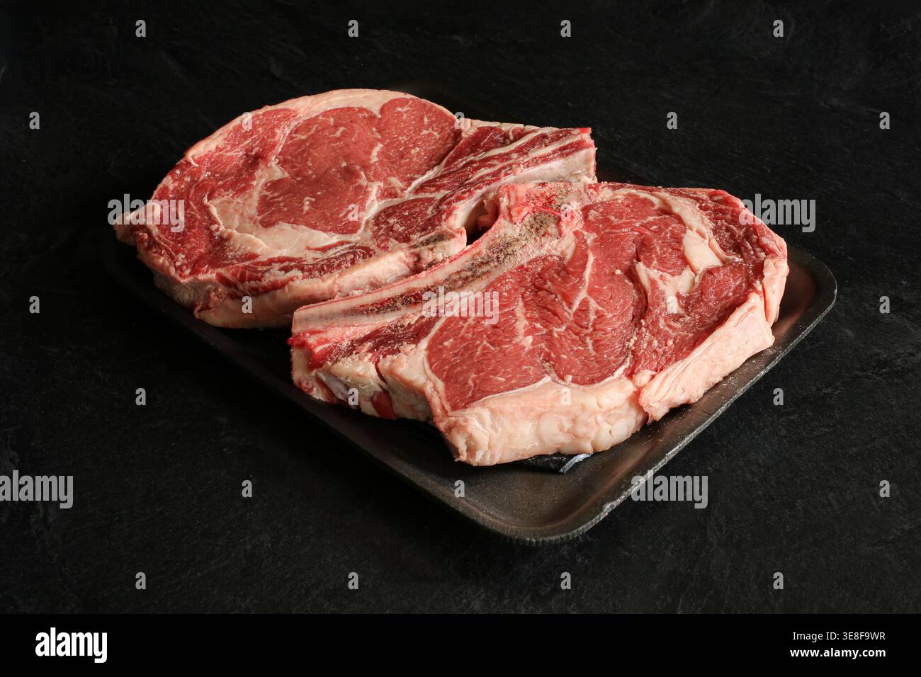 Frische Steaks mit Rippenaugen auf schwarzem Hintergrund. Stockfoto