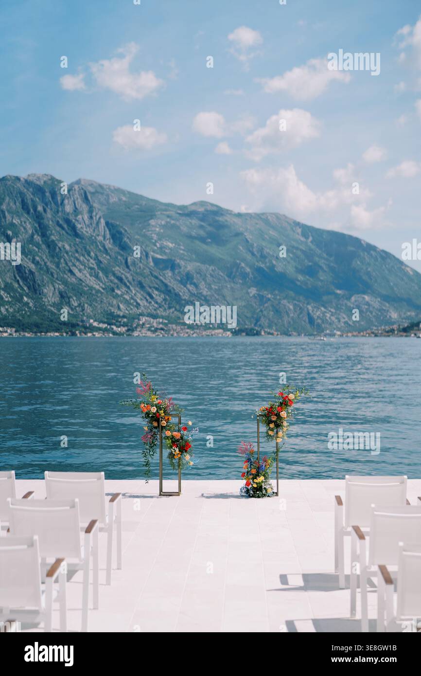 Intime, moderne Hochzeitsatmosphäre mit Blumenarrangements und ruhiger Bucht-Kulisse Stockfoto