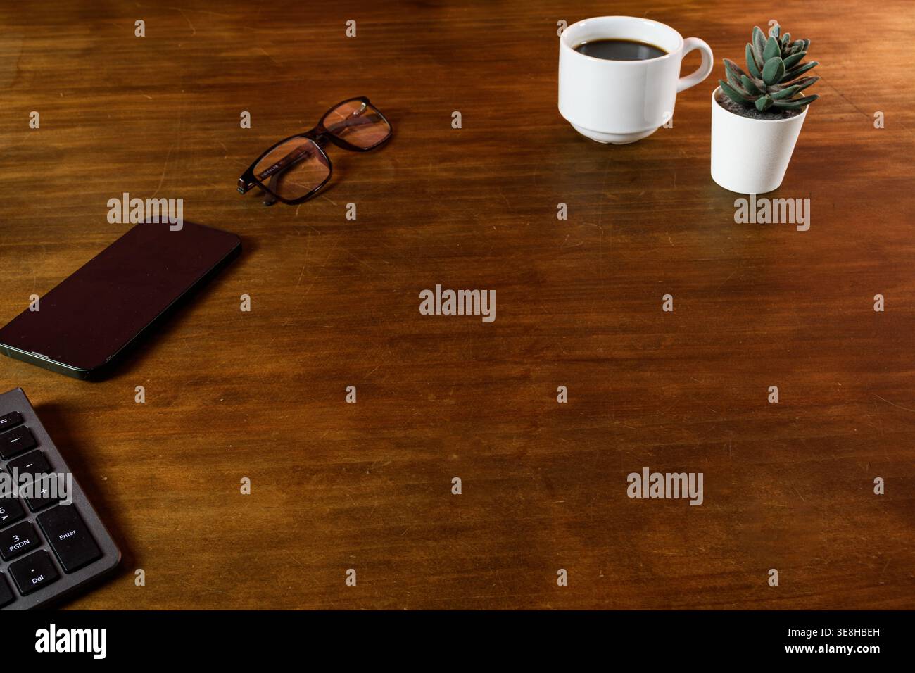 Minimaler Schreibtisch mit Smartphone, Gläsern und Kaffee, sauberer, ästhetischer Arbeitsbereich mit Kopierraum für Geschäftskonzepte. Stockfoto