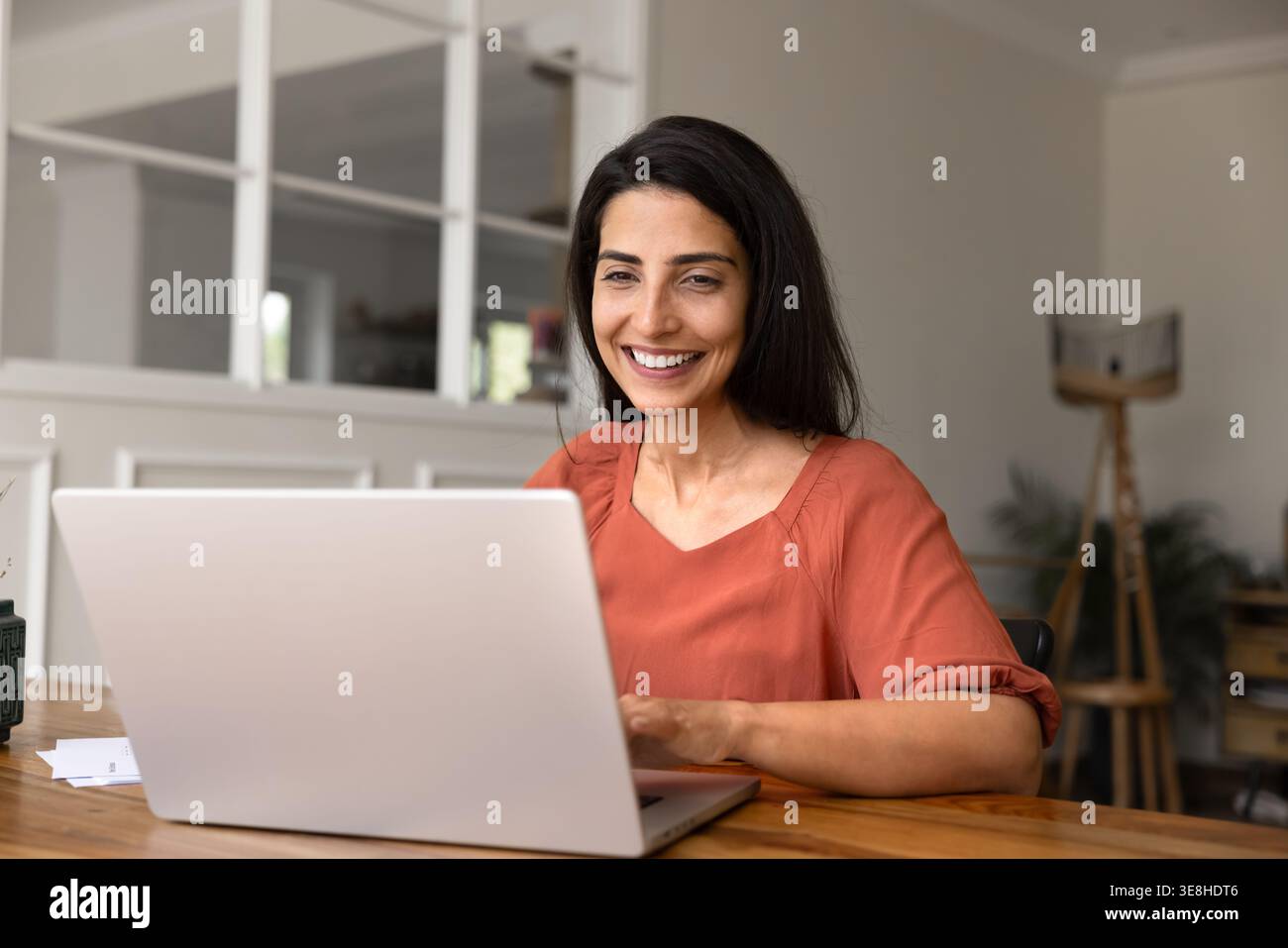 Lächelnde Frau am Laptop zu Hause arbeiten Stockfoto