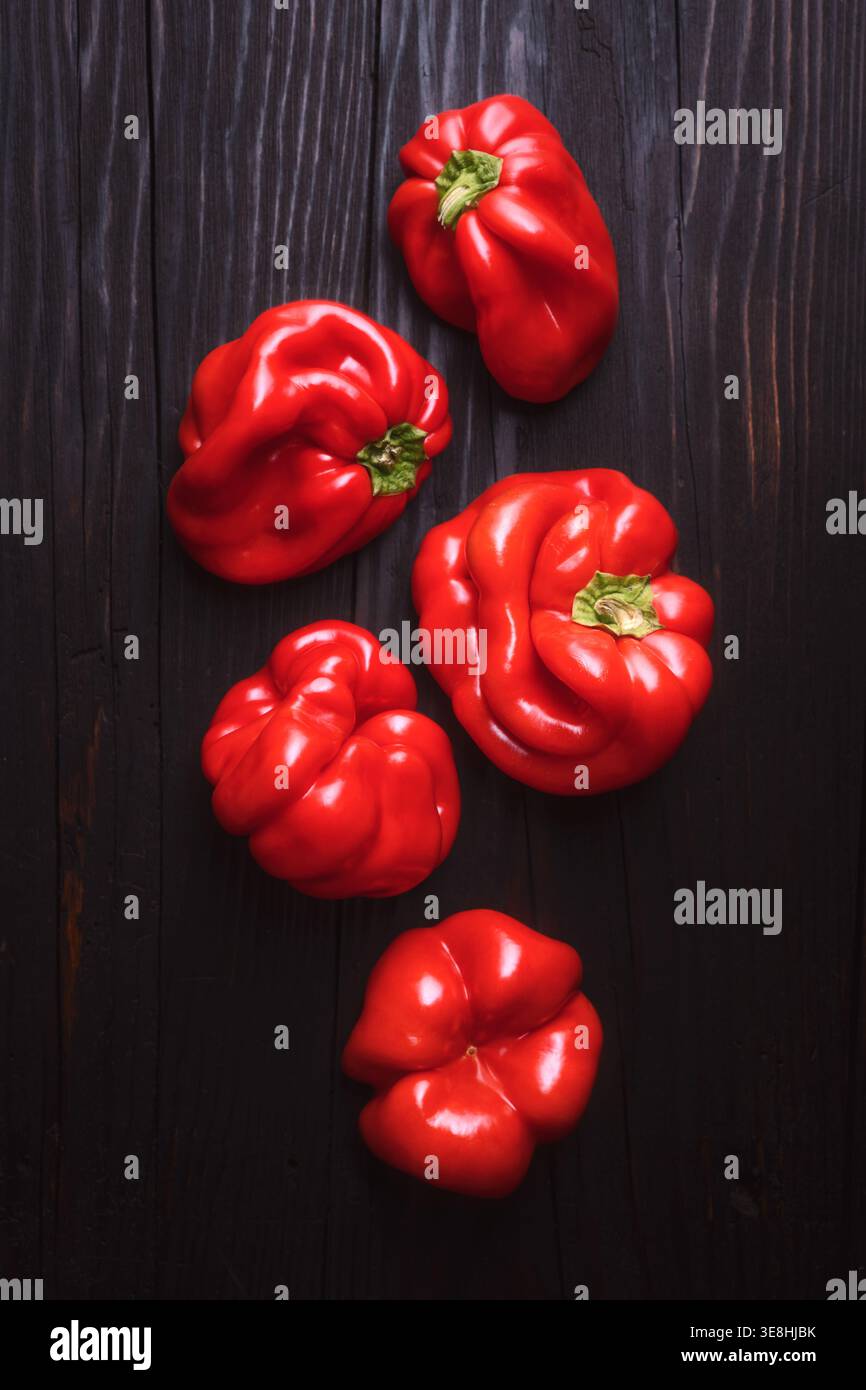 Blick von oben auf frische rote Paprika auf rustikaler Holzoberfläche. Frischer süßer Pfeffer Hintergrund, gesundes Lebensmittelkonzept Stockfoto