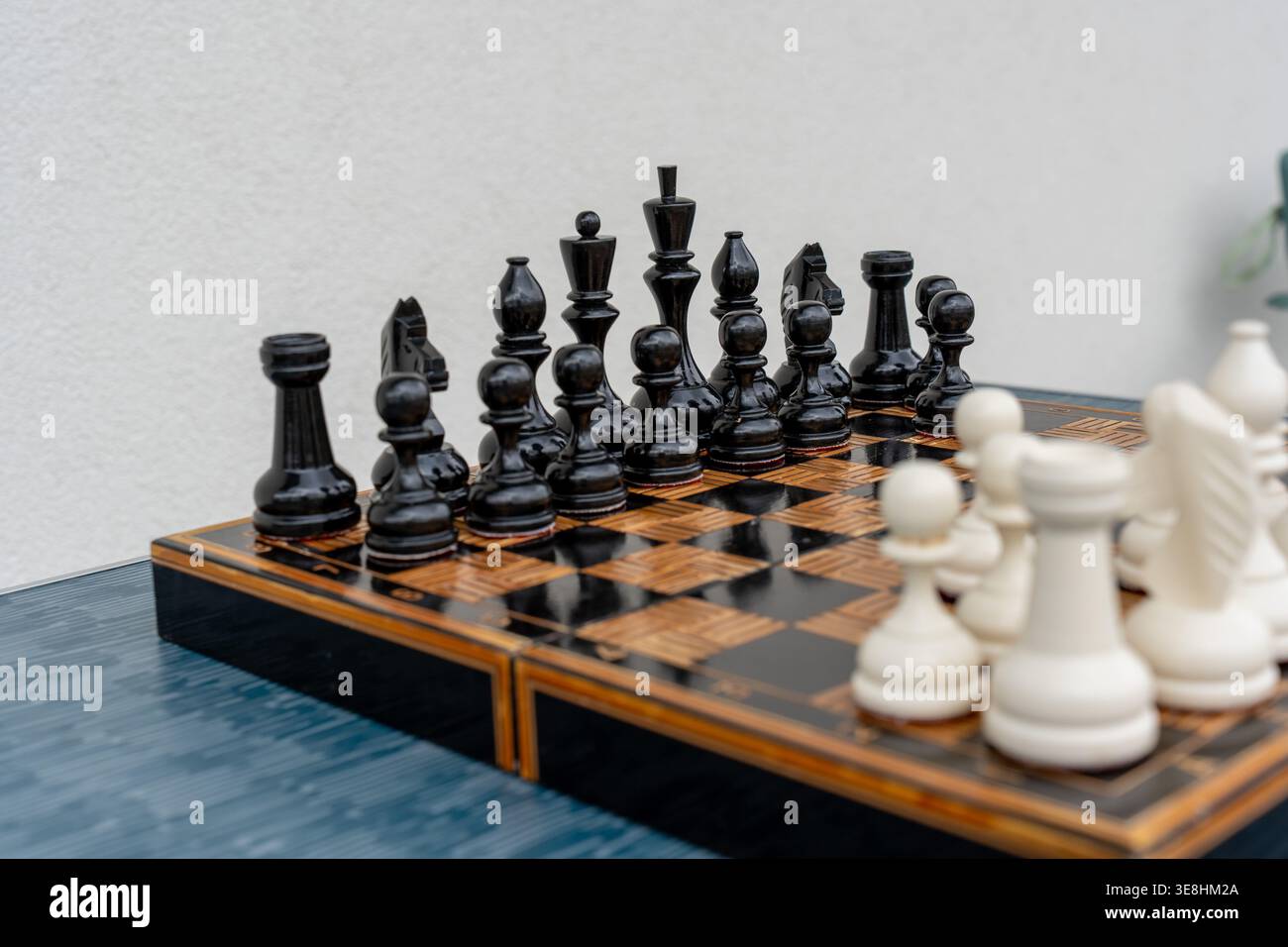 Schwarz-weiße Schachfiguren auf kunstvoll verzierten Holzbrettern bereit zum Spiel. Konzept von strategischem Denken, intellektueller Herausforderung und klassischem Brettspiel Stockfoto
