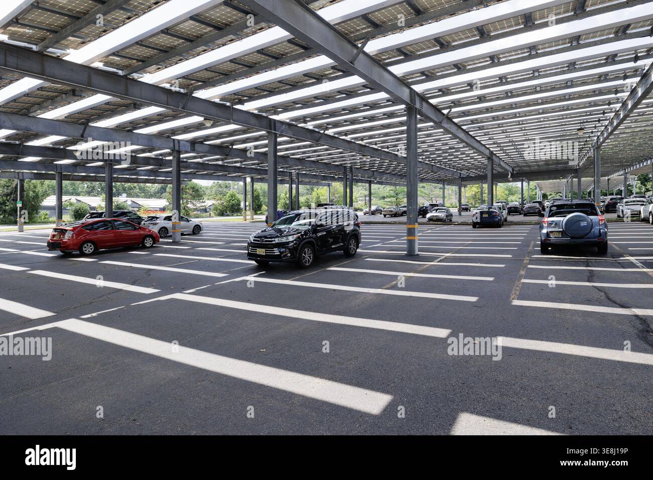 Autos parken unter einem weitläufigen Sonnenkollektor-Carport-Vordach auf einem Bürocampus in Morris Plains, New Jersey. Stockfoto