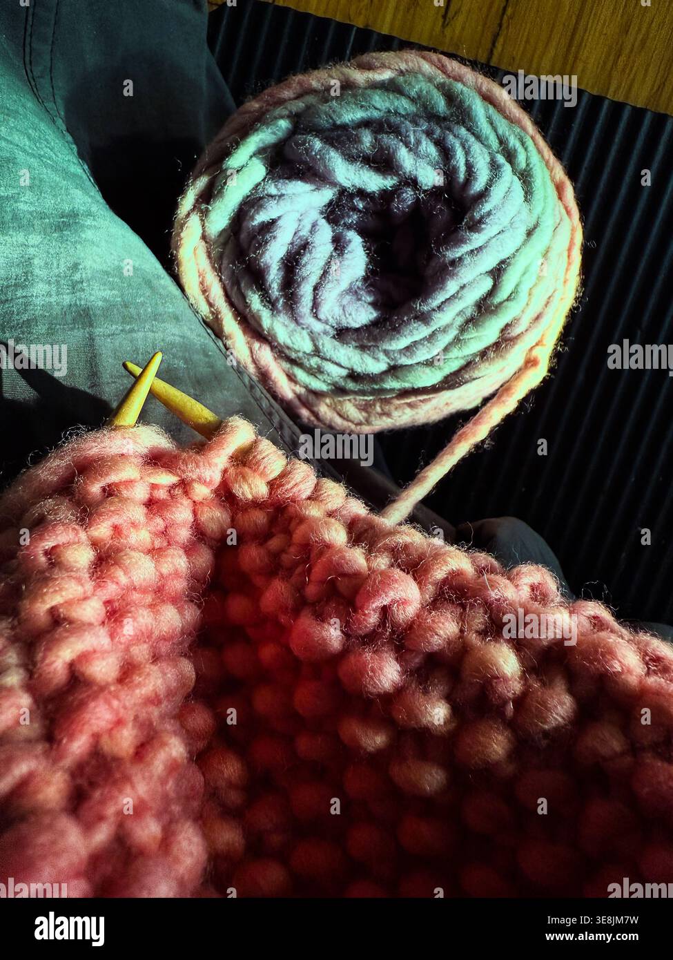 Pastellstrick mit Denim und Stricknadeln - Smartphone-aufgenommenes Stockfoto