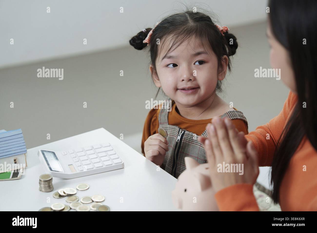 Kinder lernen zu Hause gemeinsam mit ihren Eltern, Geld zu sparen Stockfoto