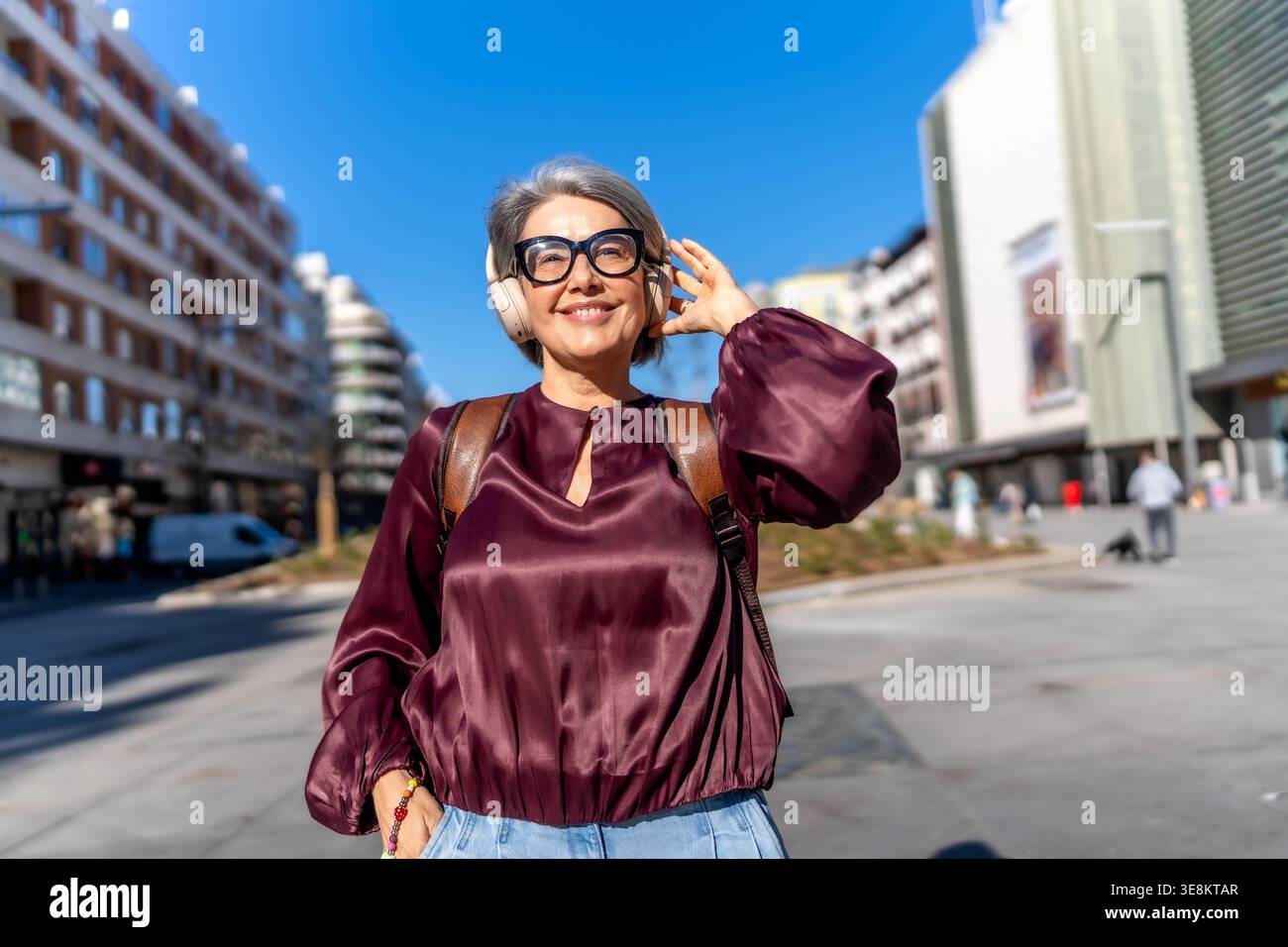 Glückliche Frau, die Musik auf der städtischen Straße hört Stockfoto