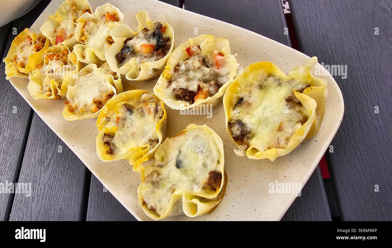 Kleine knusprige Tassen aus Teig, gefüllt mit Käse, Fleisch und Gemüse Stockfoto