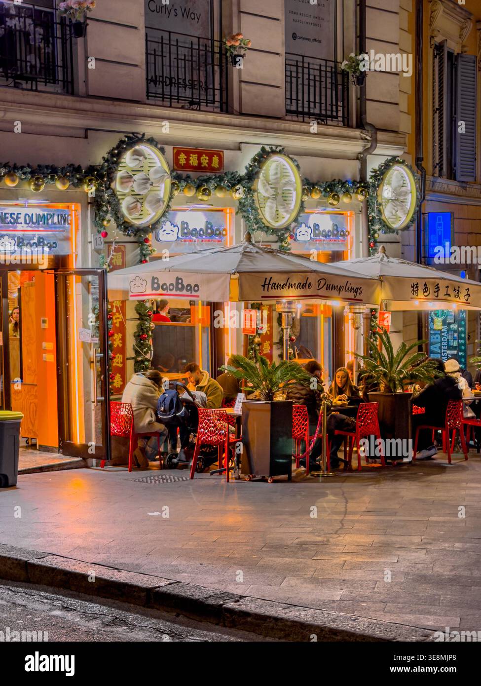 Leute, die draußen sitzen, essen im Bao Bao, einem chinesischen Knödelrestaurant am Abend auf der Via della Mecede in Rom, Italien Stockfoto