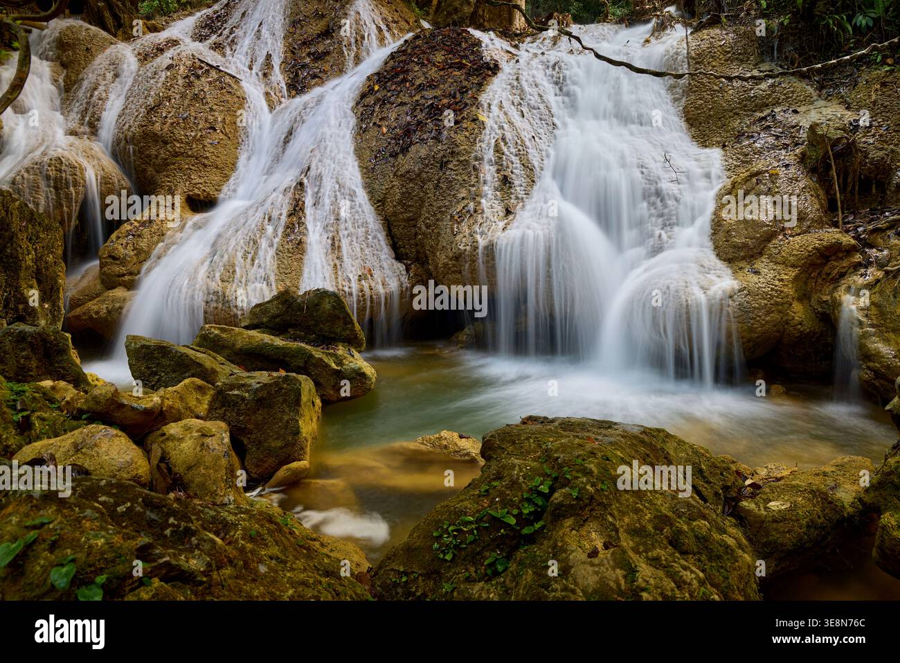 Ruhiger Wasserfall, der über Moosfelsen in einem üppigen Wald fließt Stockfoto