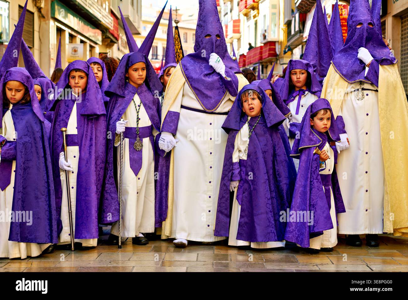 Menschen in lila Gewändern gehen zusammen während der Karwochenprozessionen in Malaga, Andalusien. Dieses Ereignis steht für wichtige Traditionen. Stockfoto