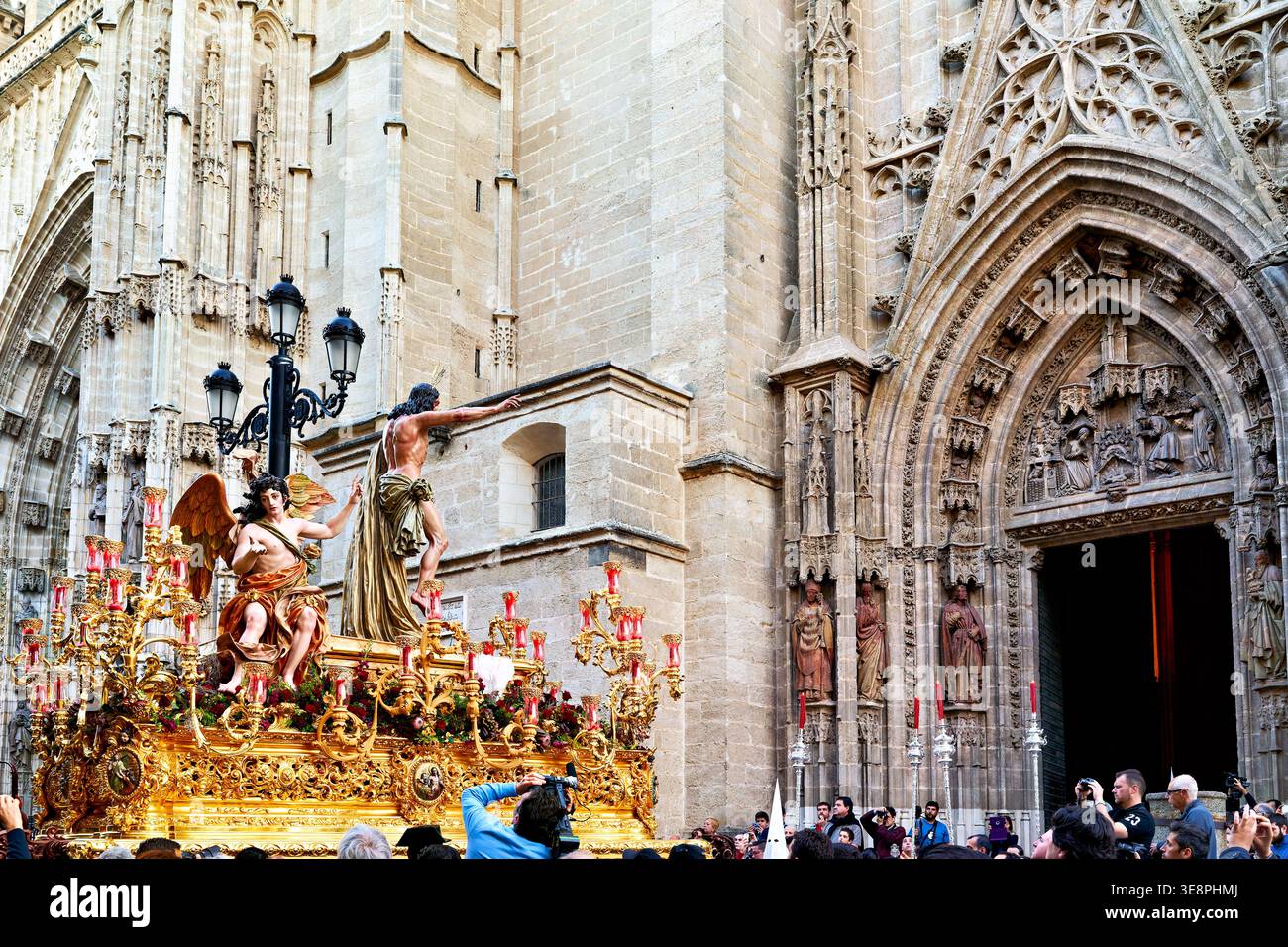 Während der Karwoche finden in Sevilla Prozessionen statt. Menschen versammeln sich um einen religiösen Wagen in der Nähe einer historischen Kirche. Stockfoto