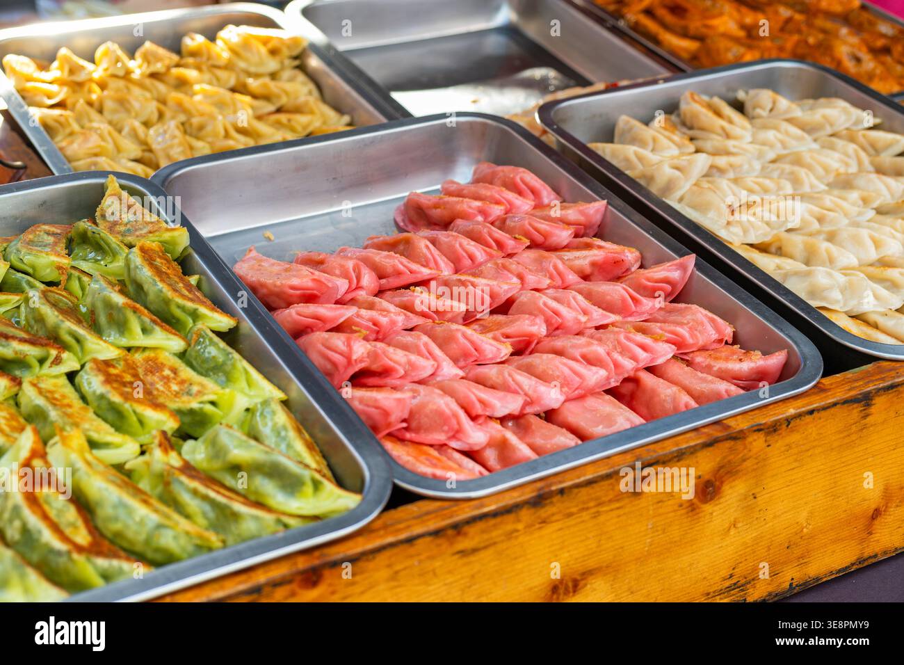 Verschiedene Teigtaschen und Dim Sum auf Tabletts auf dem Street Food Market in Phuket, Thailand. Traditionelle asiatische Snacks mit bunten Teig und Füllungen Stockfoto