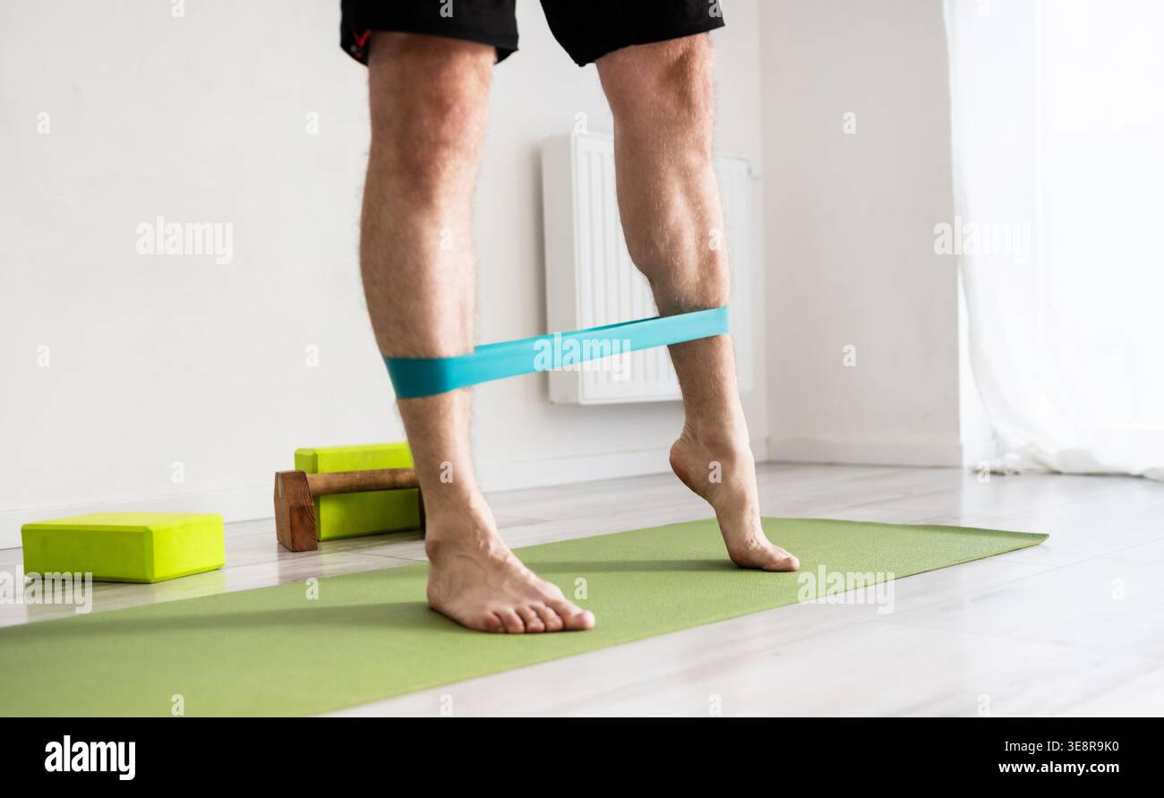 Sportliche Männer-Übungen mit Einem Gummiband für starke Beine zu Hause Stockfoto