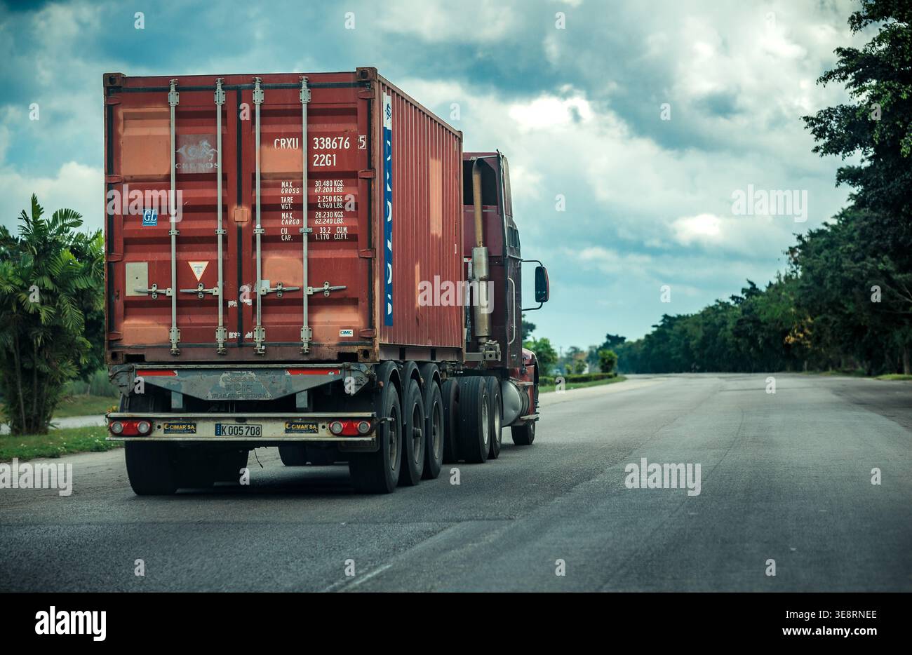 Truck, der roten Frachtcontainer auf offener Autobahn transportiert Stockfoto