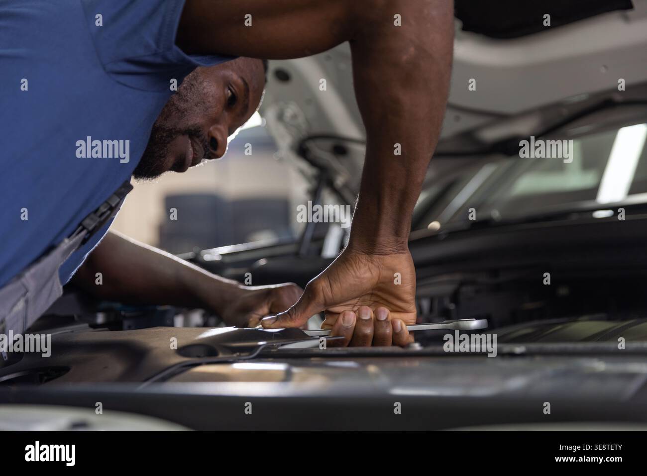 Ein erfahrener Mechaniker konzentriert sich auf die Prüfung und Reparatur eines Fahrzeugmotors in einer Garage. Stockfoto