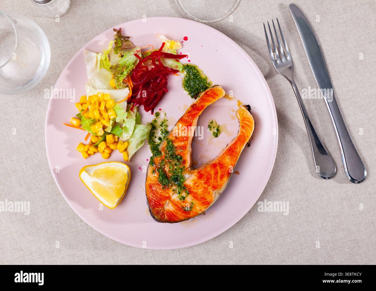 Geröstetes Lachssteak mit grüner Sauce, Gemüse und Zitrone Stockfoto