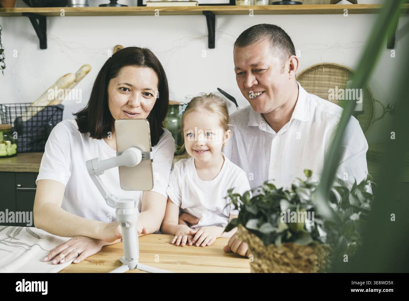 Familienspaß bei Familienanrufen. Mom, Dad und Tochter, die vier Jahre alt sind, lächeln glücklich und schauen sich den Bildschirm an. Das Konzept der Zeitvergabe t Stockfoto