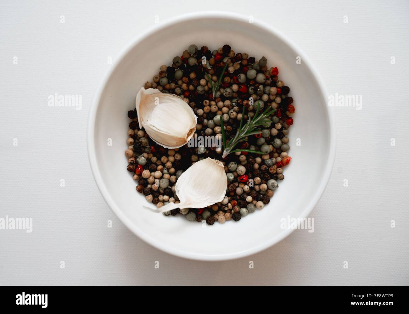 Natürliche Immunität verstärkende Zutaten Knoblauch Rosmarin und Pfeffer Mischung in minimalistischer Schüssel Zusammensetzung Stockfoto