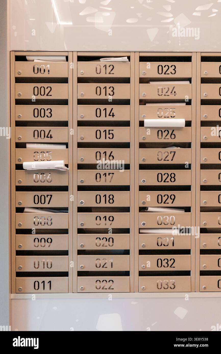 Moderne Briefkästen für Apartments mit nummerierten Fächern in der Lobby des Wohngebäudes, organisiertes Zustellsystem. Postdienst Stockfoto
