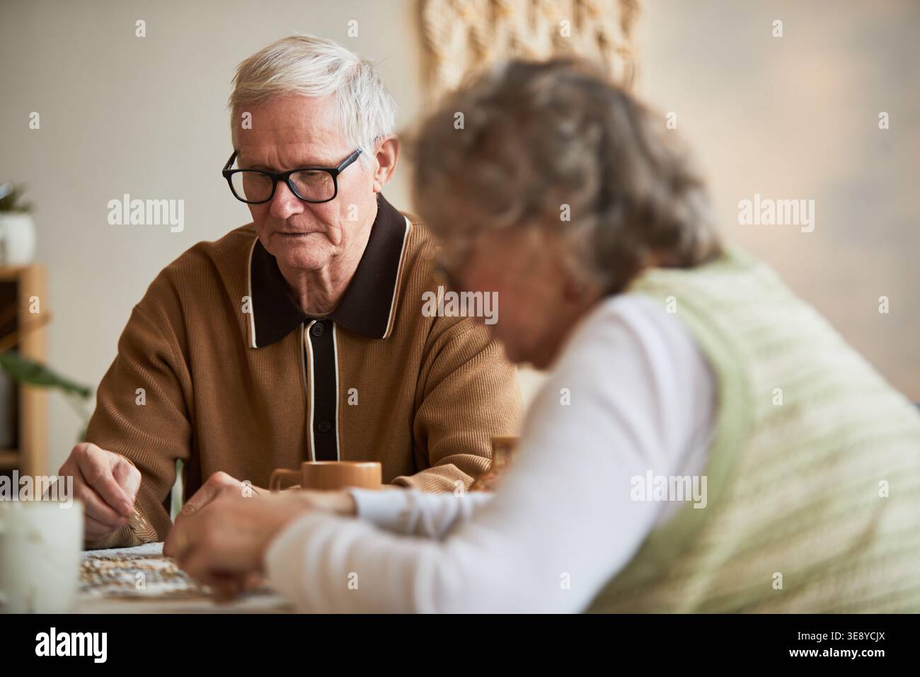 Seniorenkaukasischer Mann, der mit Seniorinnen im Pflegeheim ein Brettspiel spielt und kognitive Aktivität und tägliche Pflege unterstützt Stockfoto