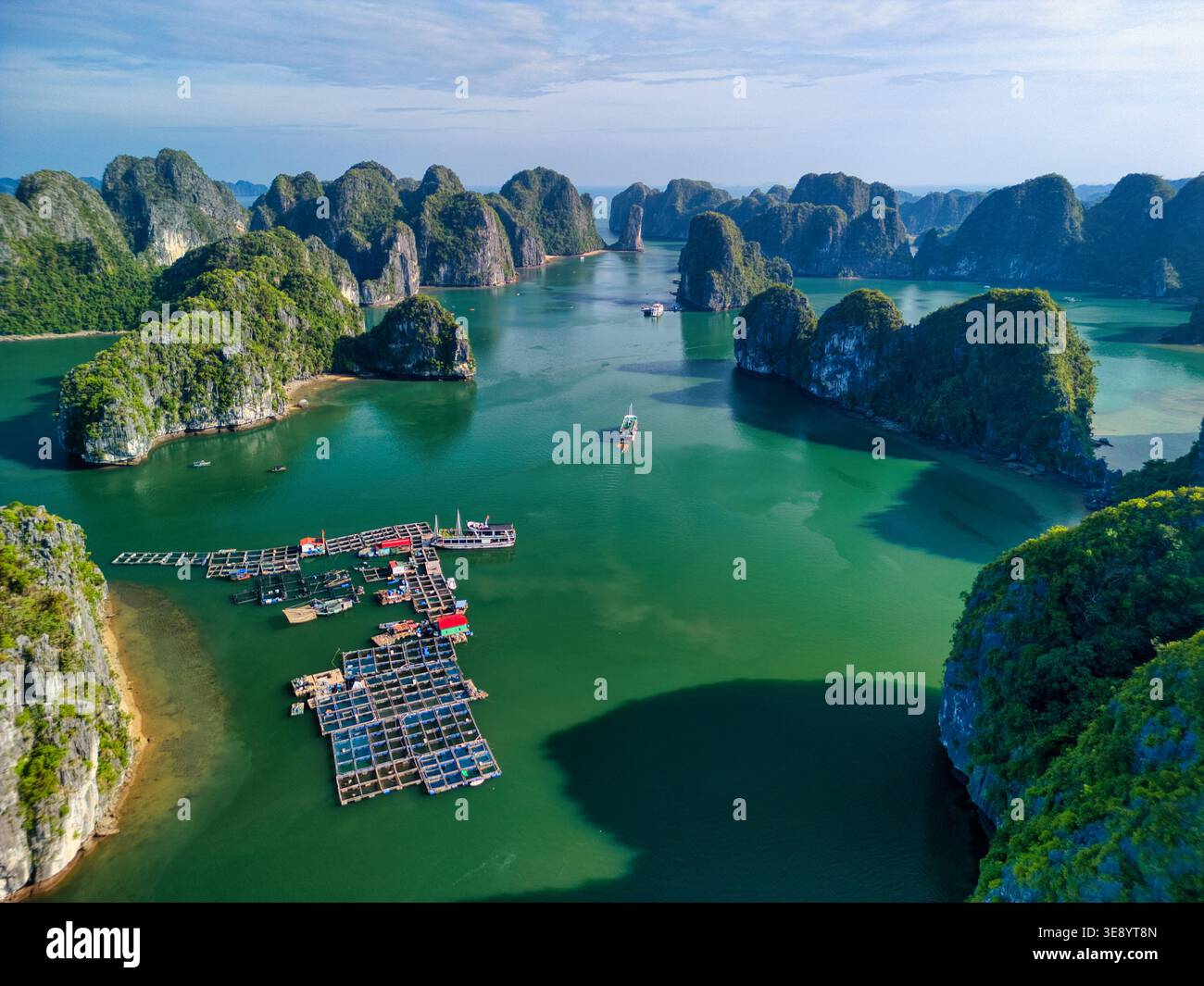 Blick aus der Vogelperspektive auf den Cat Ba Archipel mit Kalksteinkarsten, schwimmenden Fischfarmen und Booten auf türkisfarbenem Wasser in Ha Tu, Hai Phong, Vietnam. Stockfoto