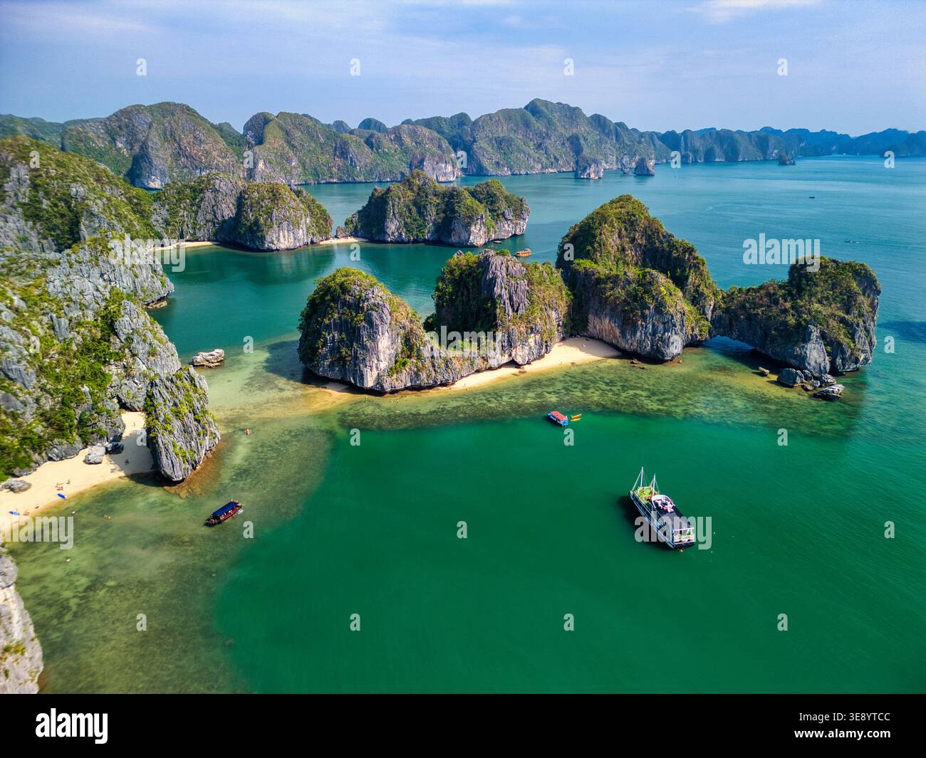 Blick aus der Vogelperspektive auf den Cat Ba Archipel mit Kalksteinkarsten, smaragdgrünen Gewässern und kleinen Booten in der Nähe von Sandstränden in Ha Tu, Hai Phong, Vietnam. Stockfoto