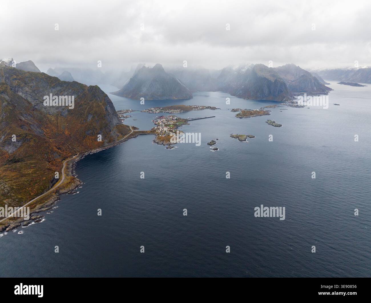 Aus der Vogelperspektive der Lofoten mit dramatischen Berggipfeln unter bewölktem Himmel und kleinen Fischerdörfern, die über den Archipel in Nord verstreut sind Stockfoto