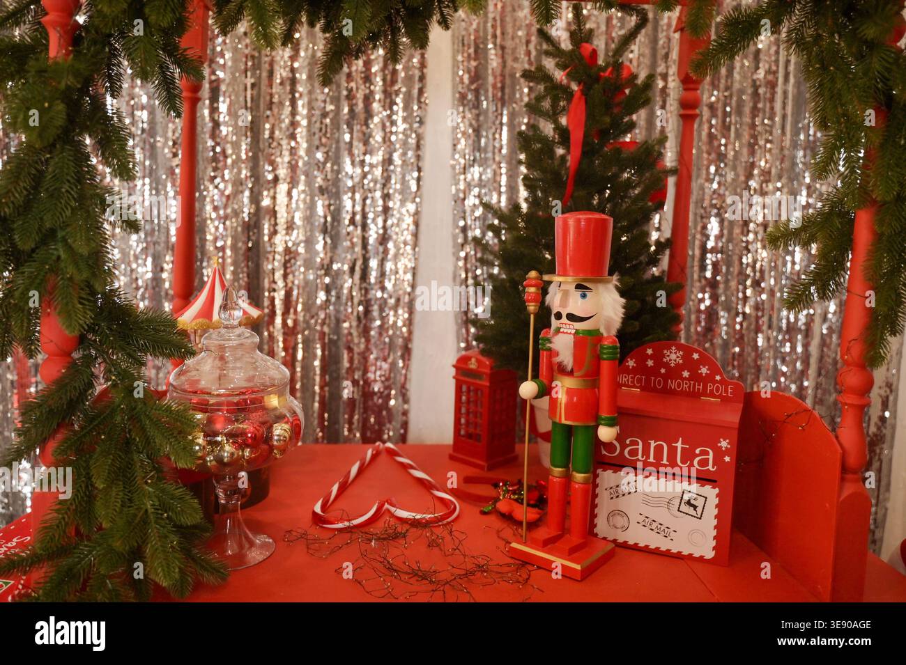 Nussknacker-Soldat und Weihnachtsmann-Briefkasten auf einem roten Wagen in einer festlichen Studio-Umgebung. Konzept von magischer Winterfeier, Urlaubstradition und Eleg Stockfoto