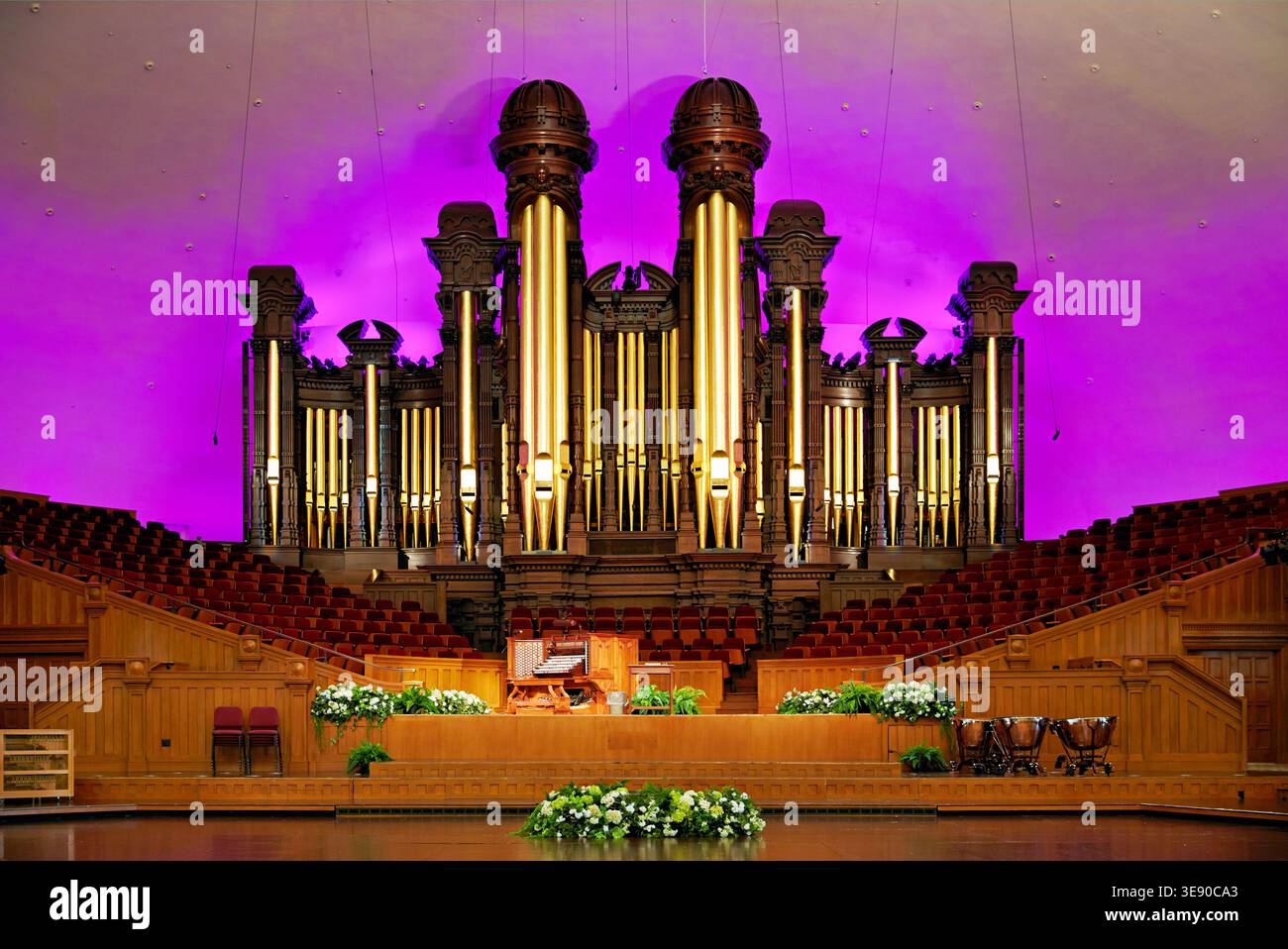 Die Tabernacle Pipe Orgel in Salt Lake City hat viele Pfeifen, die von farbigen Lichtern beleuchtet werden. Die Einrichtung umfasst Blumen und Sitzgelegenheiten in einem Innenbereich. Stockfoto