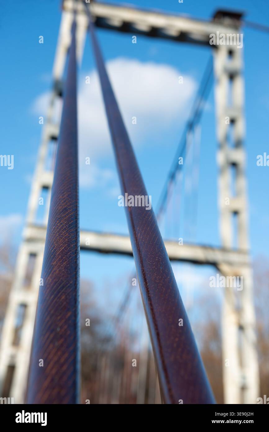 Extreme Nahaufnahme von Stahlseilen, die die Fußgängerbrücke am Flussufer in NIS (Serbien) verankern. Perspektive des Wirtschaftsingenieurwesens Stockfoto