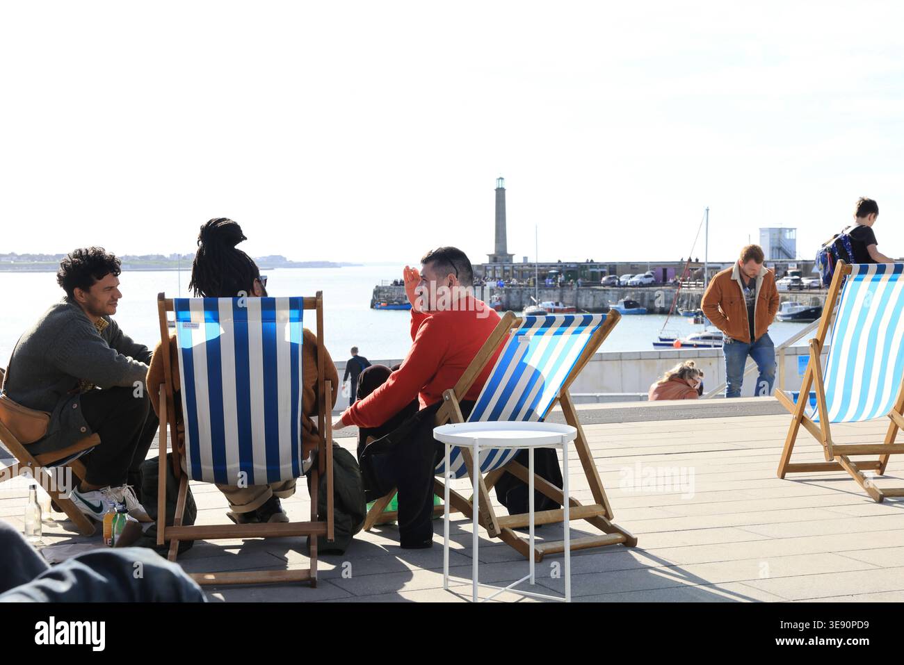 Sonnenterrasse der Turner Zeitgenössischen Kunstgalerie & Blick auf den Leuchtturm am Harbour Arm bei Frühlingswetter in Margate, Kent, Großbritannien Stockfoto